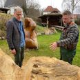 Kunstner Rune Frederiksen (th.) fortæller Jacob Kjærsgaard Mortensen, forstander på Hadsten Højskole, om status på sit arbejde med at forvandle den halvandet tons tunge egetræsklods til skulpturen "Farmand". Foto: M. Jeppesen