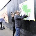 Mads Fredberg og Marie Louise Bach hjælper med at grunde hegnet på Godsbanen, der er det første ’Livstegn’, som er et samarbejde mellem street art-kunstnere og Aarhus Kommune. Hegnet er ved byggepladsen af det nye Æggepakkeriet. Det er et nyt erhvervs- og boligbyggeri udviklet af Kilden og Hindby i samarbejde med Domis og tegnestuen Sleth. Foto: Galleri Grisk