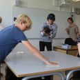 Elever fra 6.B på Skæring Skole viser, hvordan man nedbringer smitte-risikoen ved at aftørre deres borde i klassen ved hjælp af Zurface-løsningen.