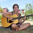 Gurli Octavia med sin uundværlige akustiske guitar i kolonihavehuset i Åbyhøj.