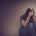 sadness young woman sitting on wood floor looking at empty dark area feeling unhappy and afraid on white wall background with battered abused woman concept.