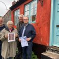 Jytte Andersen som i 1976 lavede det første Ebeltoft-julemærke, holder dette års frimærker. Sammen med tre repræsentanter fra Lion Mols har de taget opstilling foran det hus i Nygade i Ebeltoft, som i år udgør motivet. Forrest til højre står Bent Laursen, som holder årets lodseddel, bagved ham står kasserer Thomas Brøgger og ved siden af ham præsident Egon Madsen. Foto: Anne Frank Henriksen