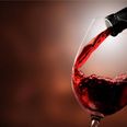 Red wine pouring in glass on background