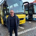 En pendler, der arbejder for Din Avis Aarhus, poserer foran en togbus ved Aarhus H. Foto: Smilende kvinde i gul vest